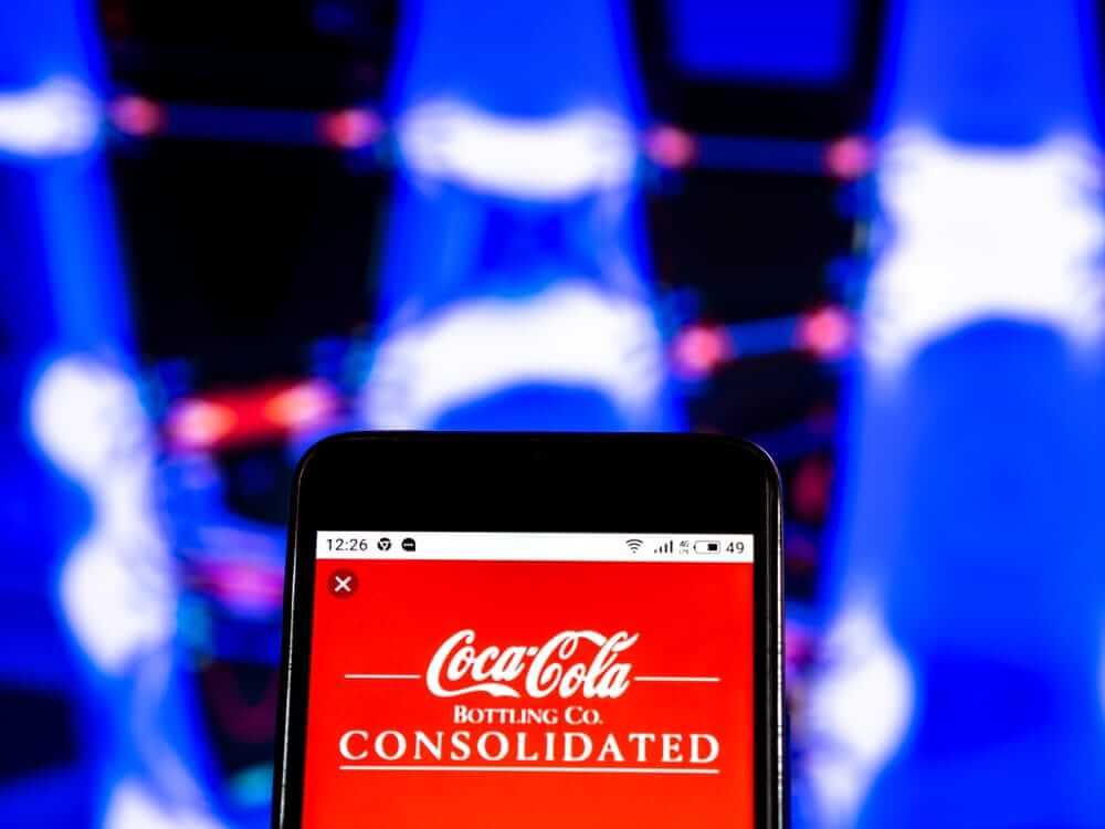 Coca-Cola Co on phone with blue background by- IgorGolovniov via Shutterstock